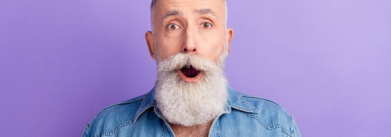 an older man with a trimmed white beard looking surprised at the tips he is receiving