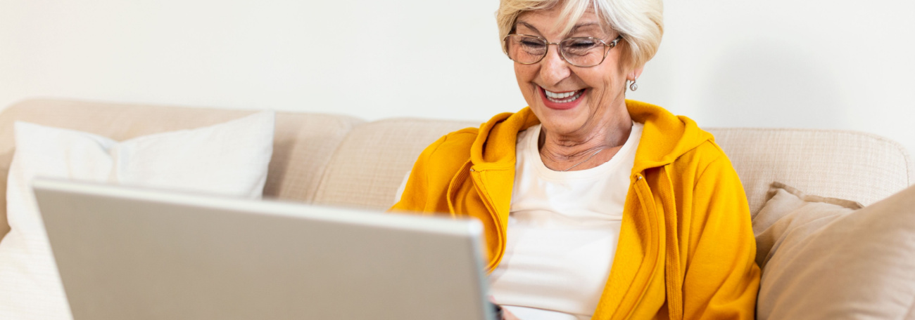older woman sitting on her sofa playing online casino games on her laptop 