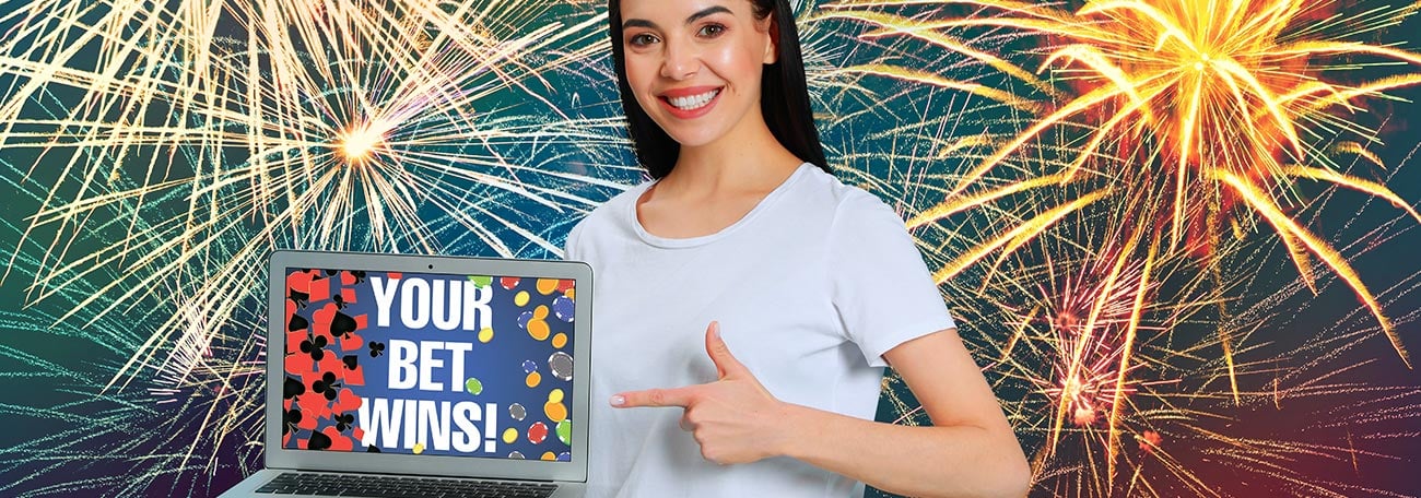 happy young woman pointing at laptop that says your bet wins with fireworks in the background