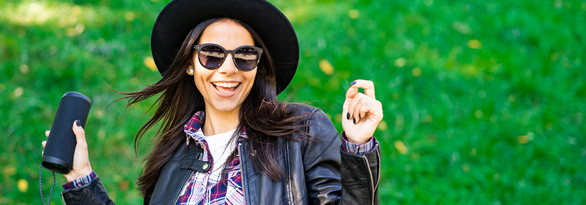 young woman in casual dress:a denim jacket, a flannel shirt, a wide brimmed hat, and sunglasses in joyous reverie