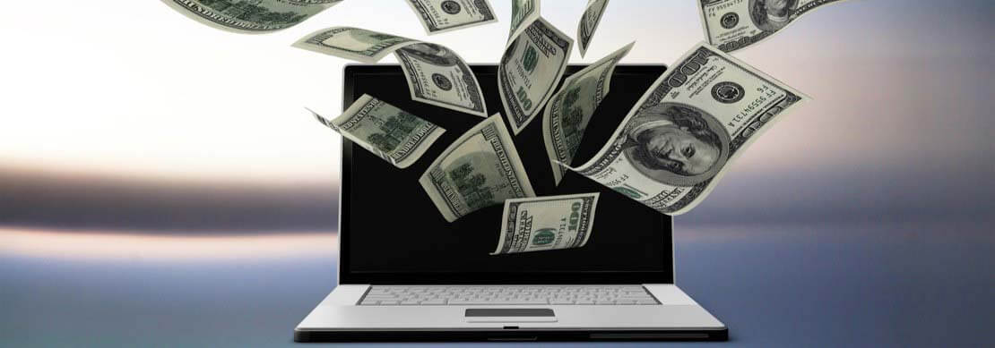 laptop with money flying out of it