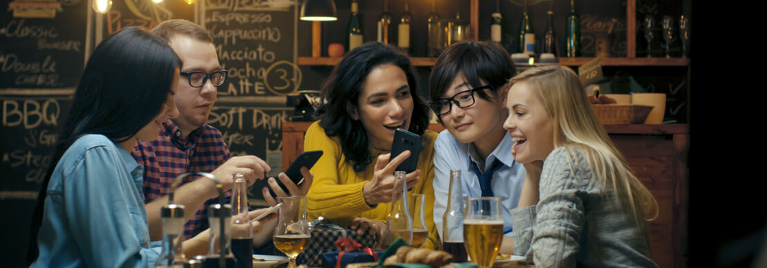 friends at a restaurant showing each other their wins on their phones