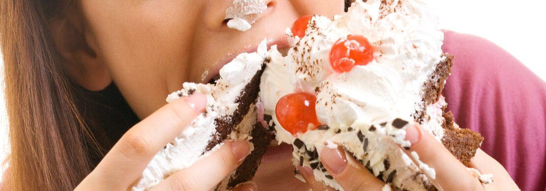 woman eating a very messy cream cake with strawberries