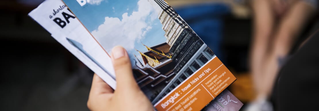 hand holding travel brochures to Bangkok