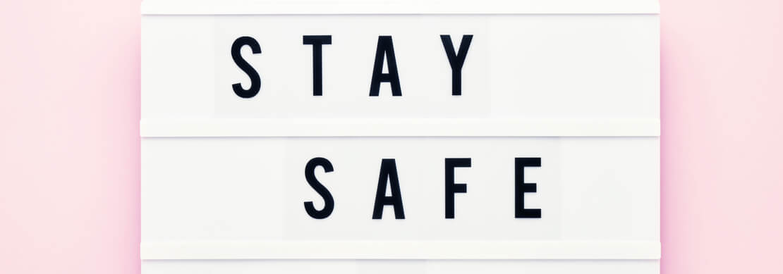 words Stay Safe and a heart written on a white board on a pink background
