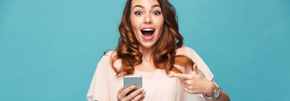 girl pointing to her phone to show she won playing a slot