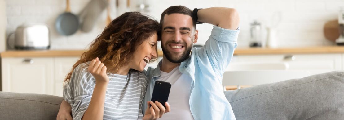 couple sitting on the sofa winning at slots at Jackpot Capital casino