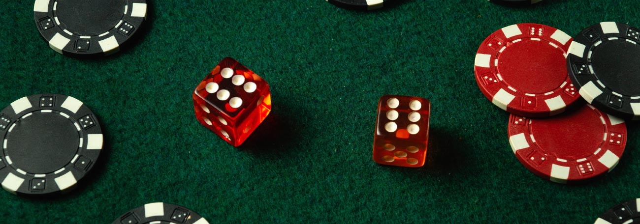 black and red casino chips and red die on a green felt table