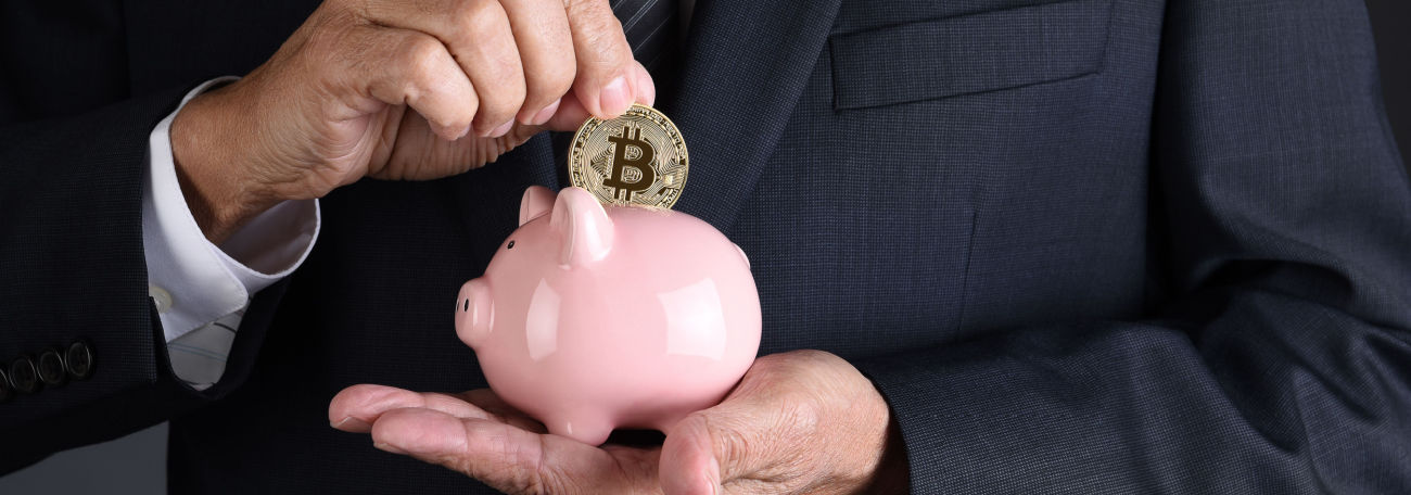 a man in a business suit depositing a bitcoin in a piggy bank showing the flexibility of bitcoin as a a real currency