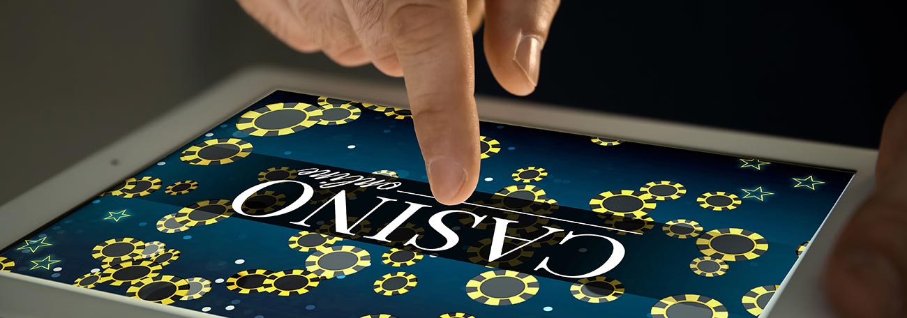 man tapping a tablet screen that says casino online and has casino chips on the face of the tablet