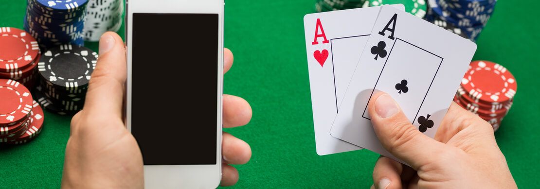 a picture of a gamer holding a smartphone and a pair of aces with poker chips of many colors in the background