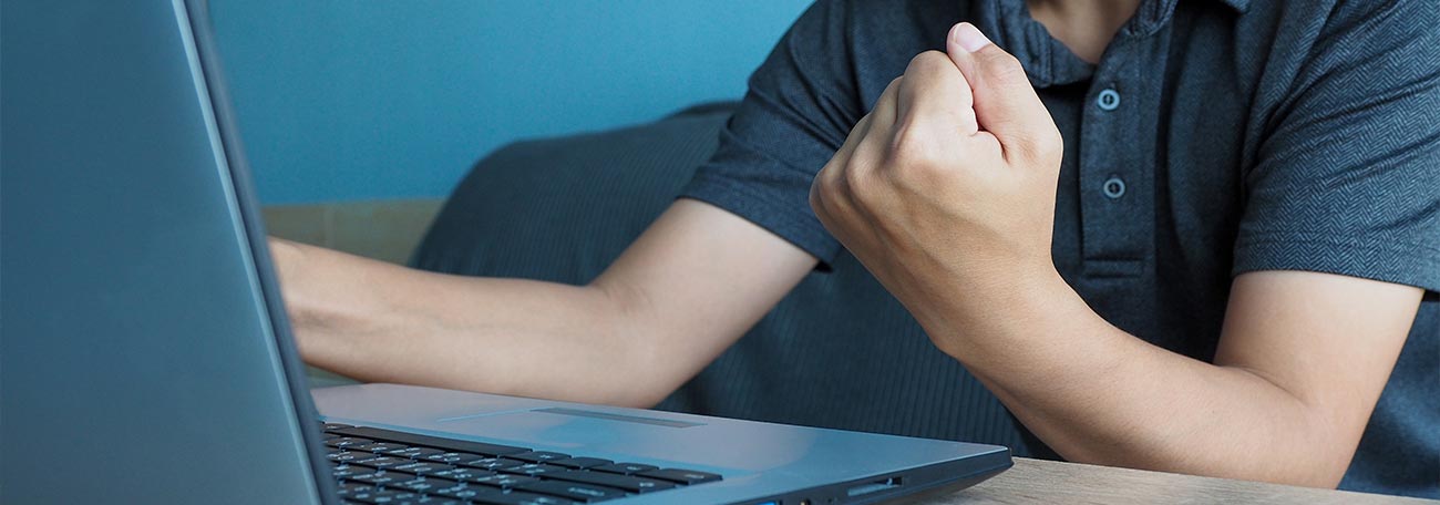 young man enjoying playing games on his laptop computer