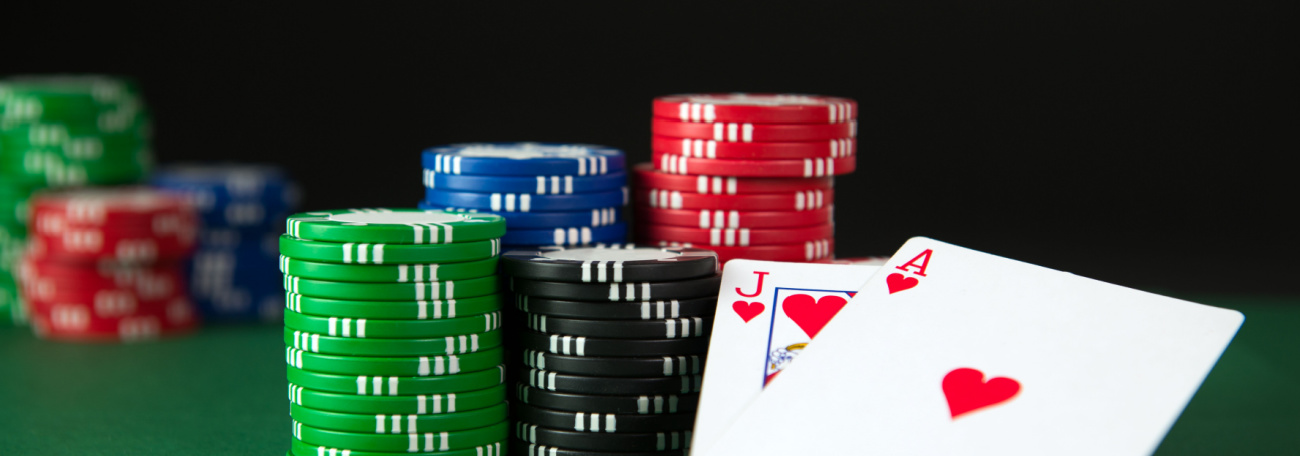 a blackjack of an ace and jack of hearts on a blackjack table with casino chips stacked behind the cards 