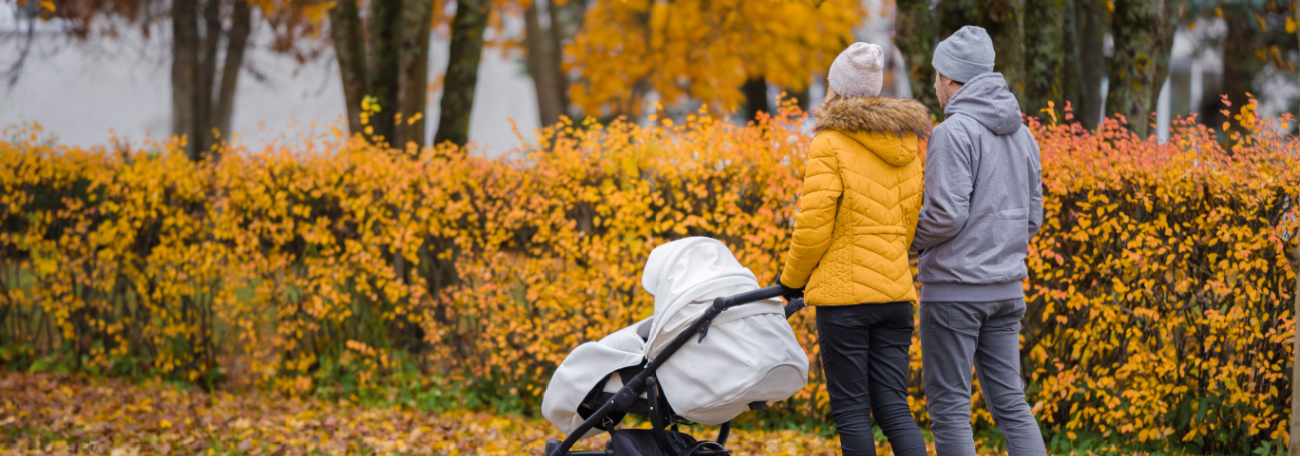 a relaxed young couple pushing a white baby stroller in a small town in the fall