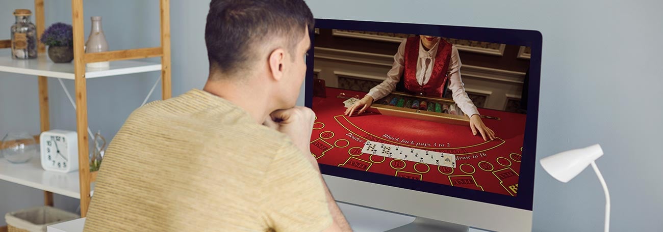 a young man playing live blackjack on his laptop through an online casino