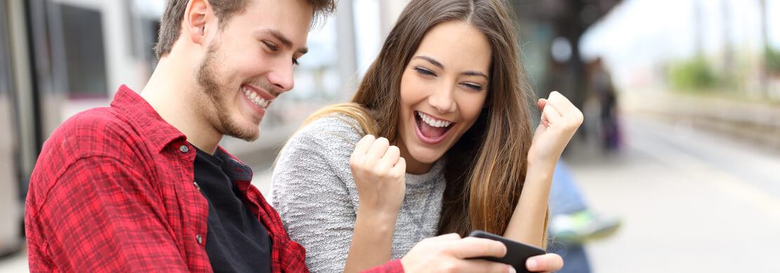 young millennial couple happily enjoying online casino gaming on their smartphone