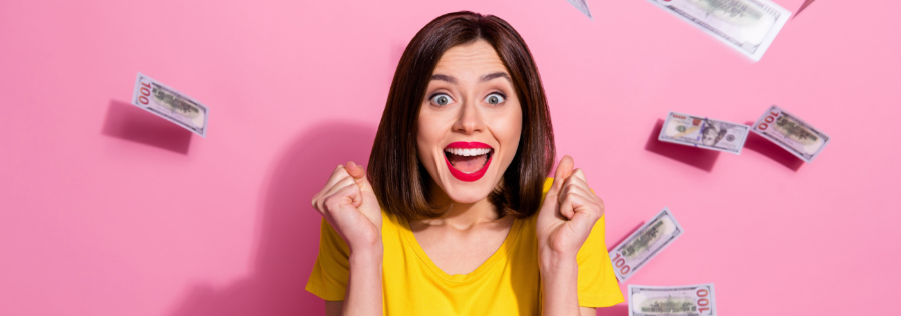 young woman in yellow top with bright red lipstick and brown hair celebrating a jackpot win with money floating in air