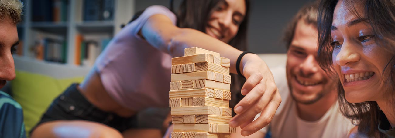 four young adult friends enjoying Jenga, a game of both skill and chance