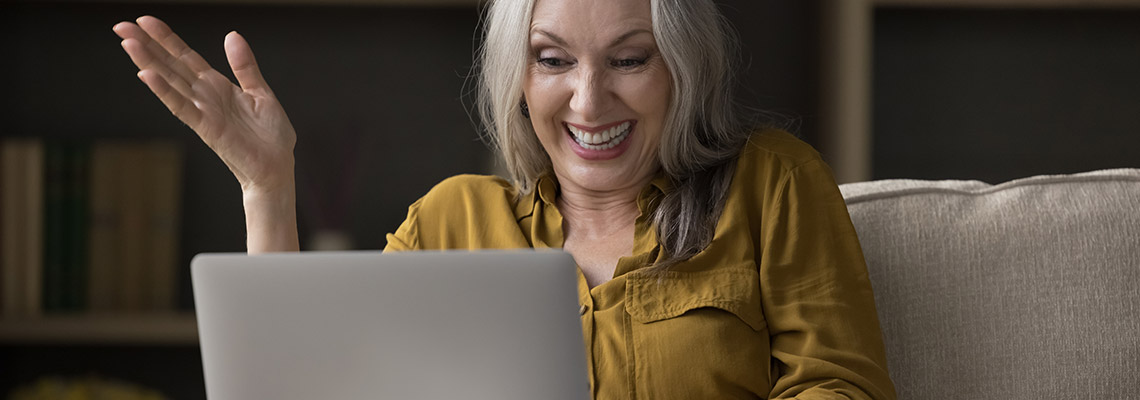 a middle-aged woman enjoying playing online casino games on her laptop while sitting comfortably on her sofa