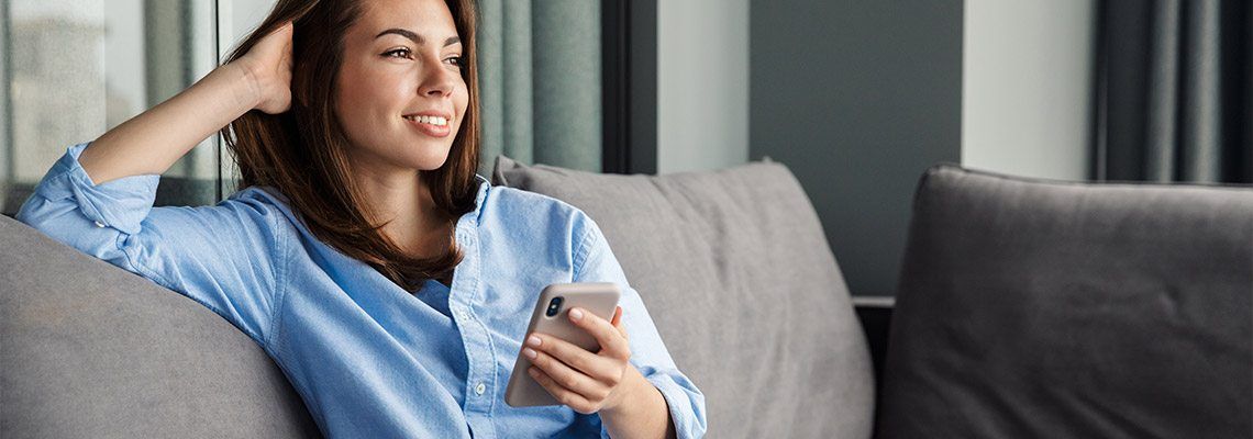 a young attractive woman enjoying playing casino games on the sofa on her smartphone