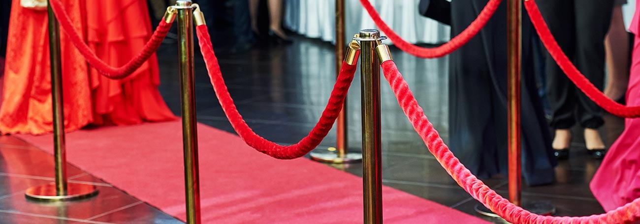 people milling about at an event with the red carpet in the foreground symbolizing the VIP Club