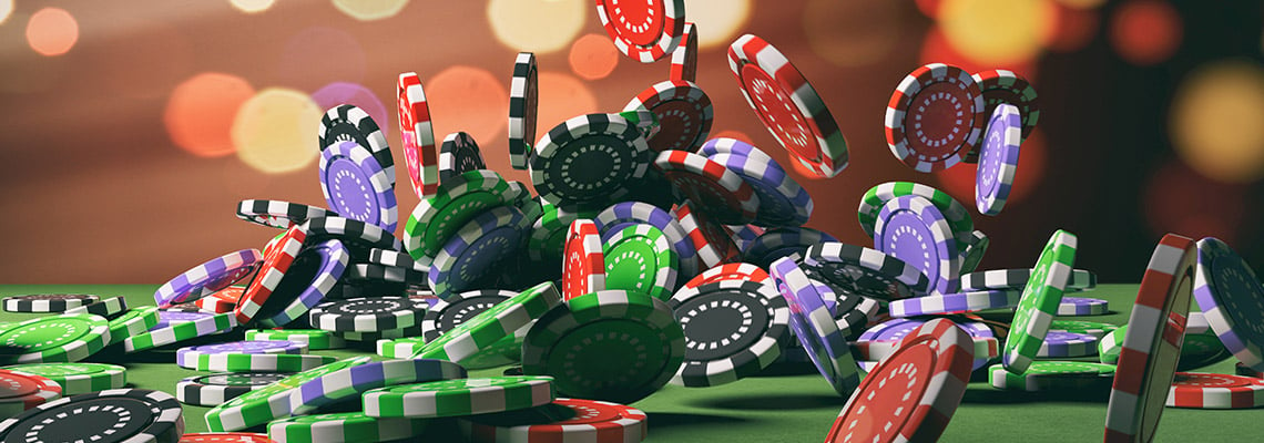 a cascade of casino chips in green, red, blue, and purple falling onto a green felt casino table