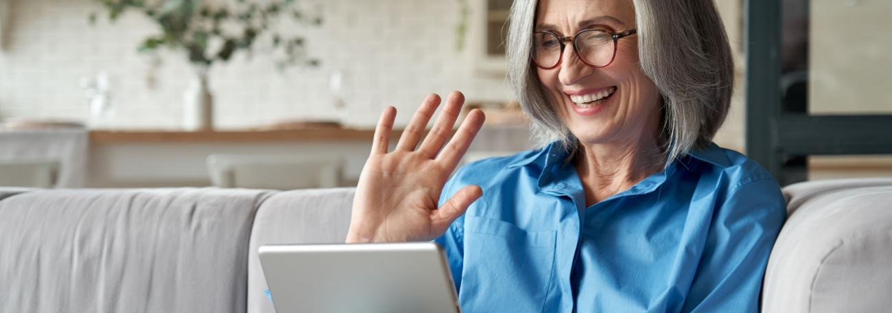 a grey and proud older woman enjoying herself gaming on her tablet, comfortably on her sofa