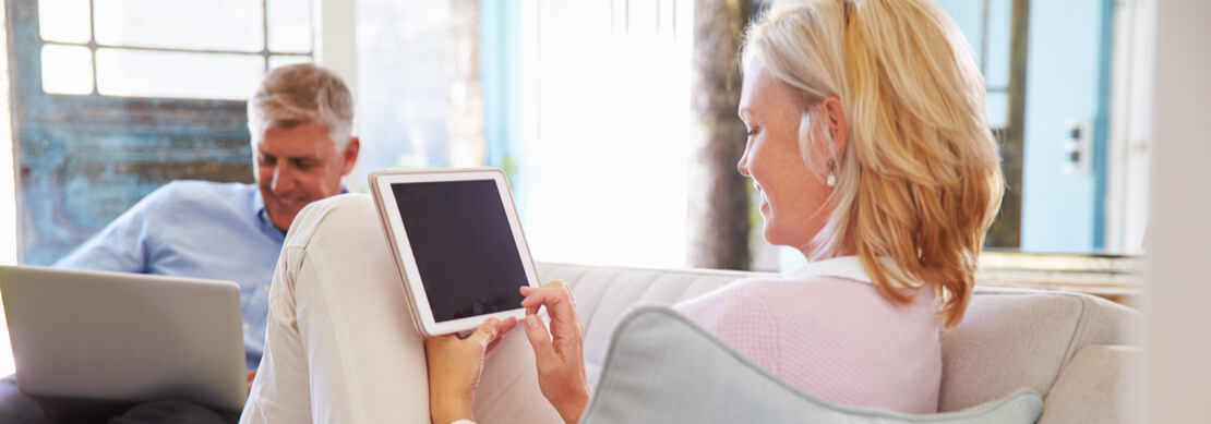 happy middle aged couple on laptop and tablet