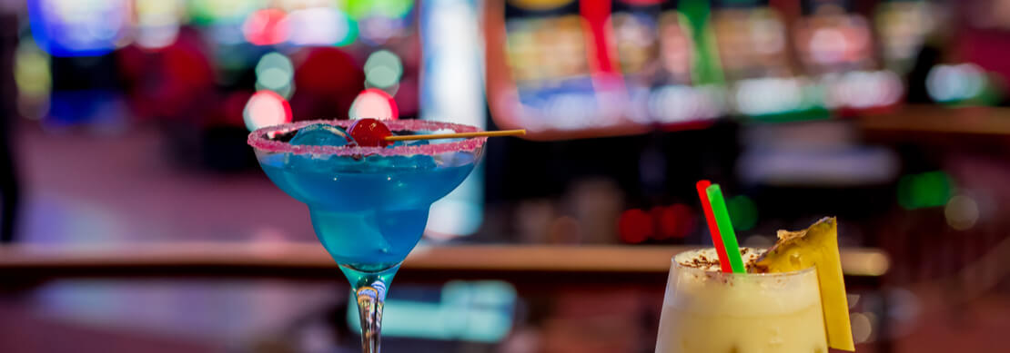 the edge of a roulette table with two drinks sitting there but no people around