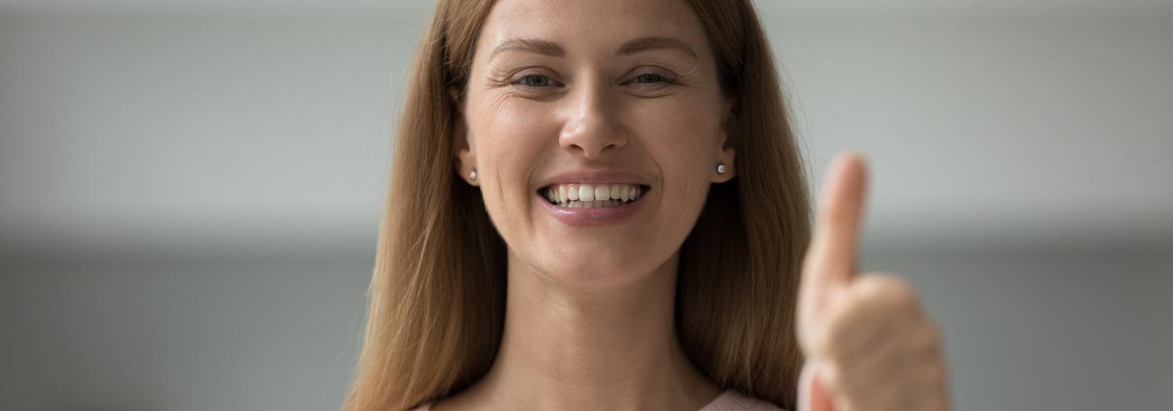 attractive young woman with long straight brown hair and a great smile showing the thumbs up signal after getting good advice