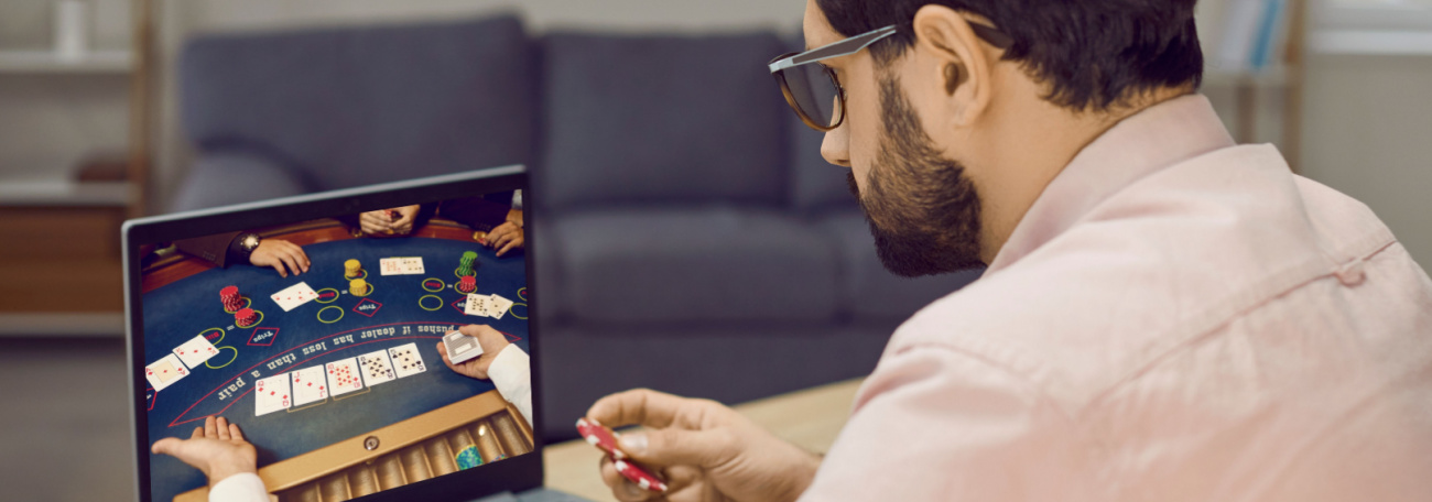 young man with short cropped dark beard playing a casino game on his laptop