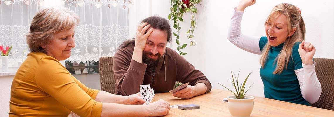 Young couple playing a card game with the mother of one of them shows the value of playing games to solidify family ties