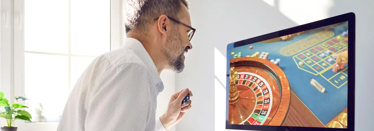 a man with a short goatee playing casino games on a large screen