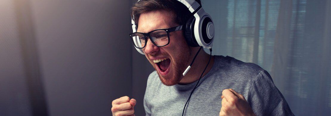 happy gamer playing at Jackpot Capital on his computer with headphones on