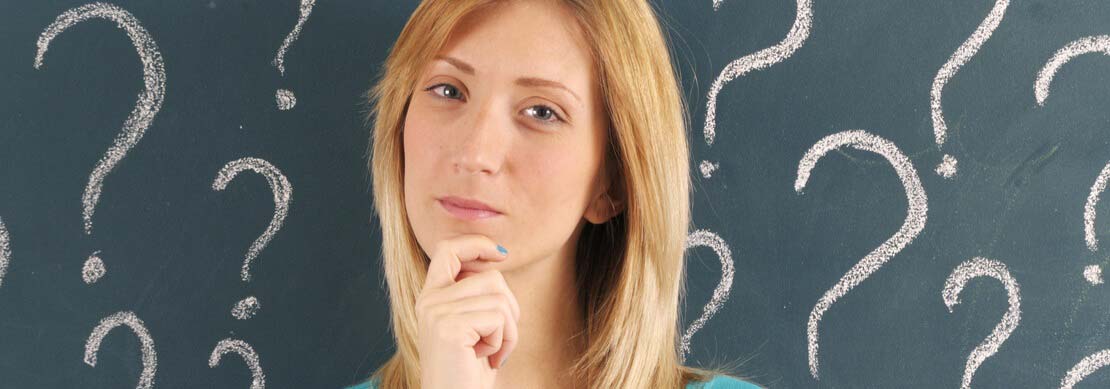 woman looking quizzical with question marks on the wall behind her