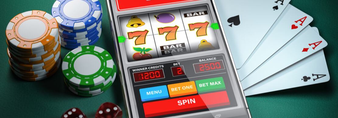a hand held mobile device with the retro symbols of 7s showing on the screen and chips, dice, and four aces surrounding the mobi
