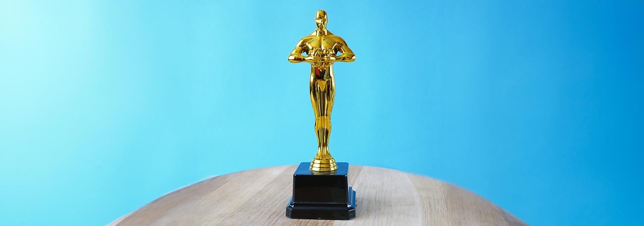 the Oscar award standing on a wooden table against a light blue background