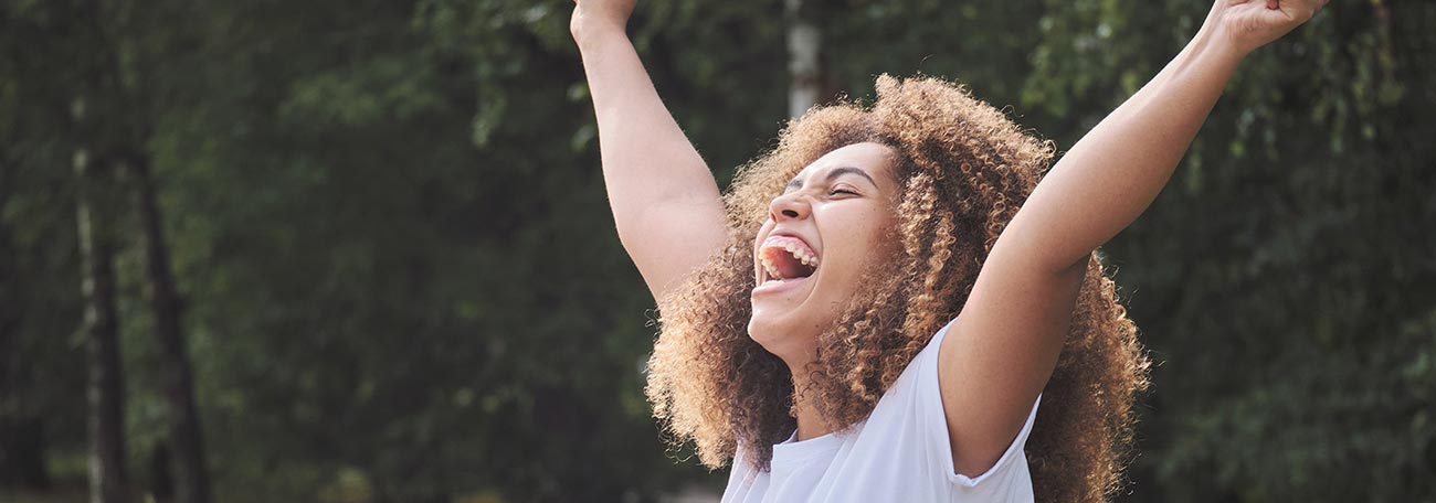 unbridled elation as a young woman throws her hands up as she wins a jackpot playing on her laptop in a city park