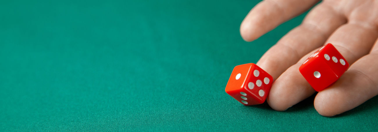a man rolls two beautiful red die onto a green felt table 