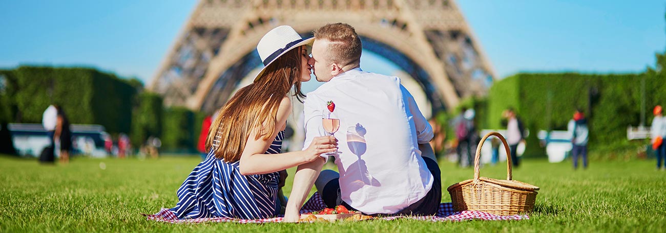 a young coupe having a romantic picnic on the grass in the shadow of the Eiffel Tower