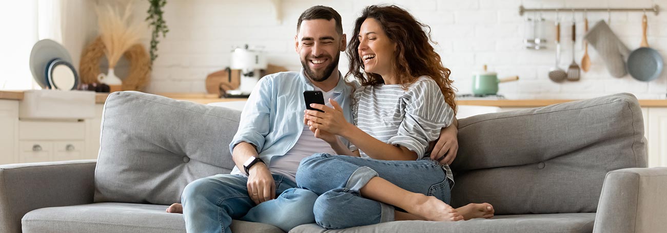 happy couple playing online roulette while relaxing on their sofa