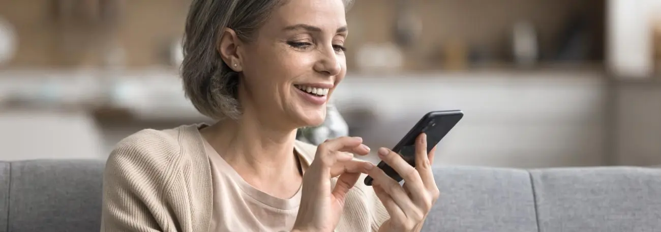 an attractive middle aged woman with salt and pepper hair enjoying casino games on her smartphone