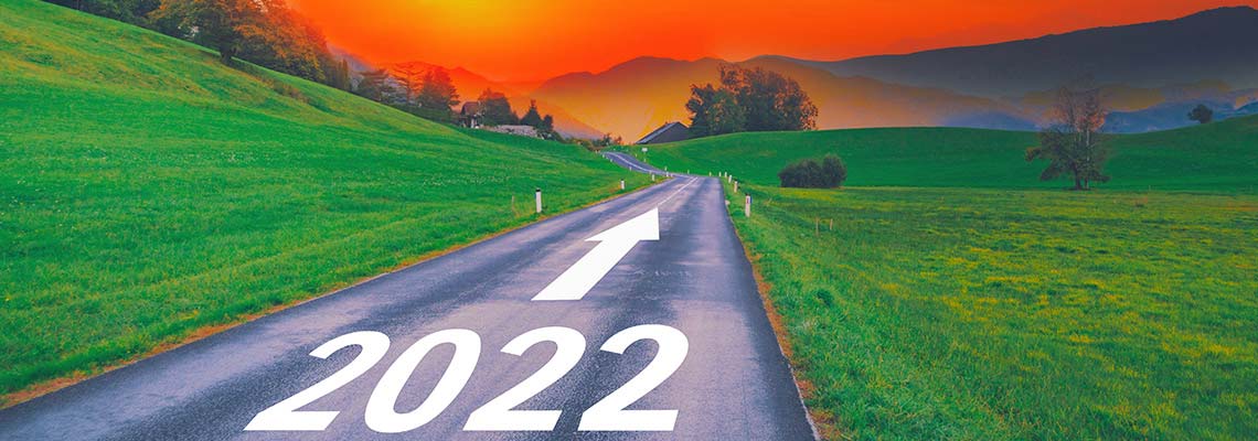 long open two lane highway with bright, gold sunrise in the background and 2022 painted on the road