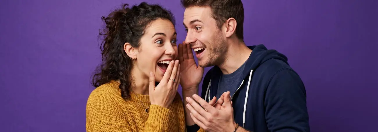 two young adults happily sharing a secret 