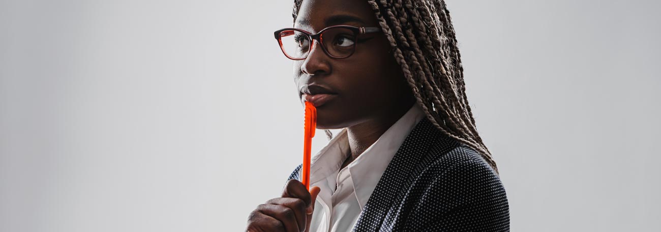 an attractive African-American woman with corn rows in a business suit in deep thought looking out at a distance