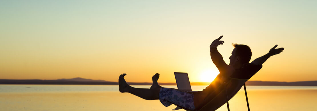 happy gamer sitting in a beach chair on the beach celebrating a Jackpot Capital win on his laptop